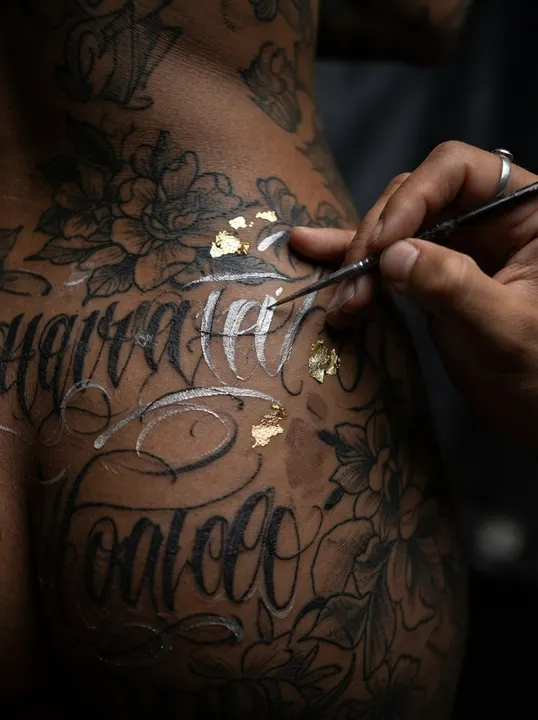 AI image: A brush adding silver script to tattooed skin