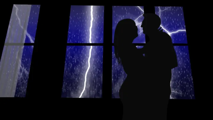 Silhouette of a couple embracing at a window during a lightning storm