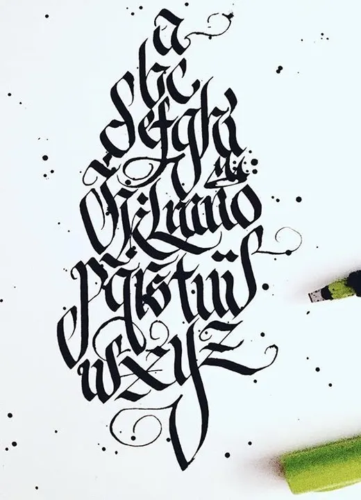 A full blackletter alphabet in black ink stacked down white paper, with green markers