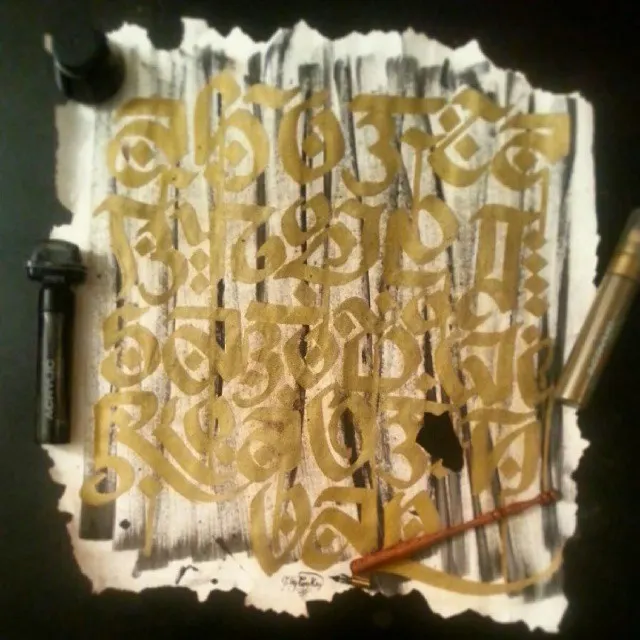 A gold blackletter alphabet on torn paper, with brushes and markers