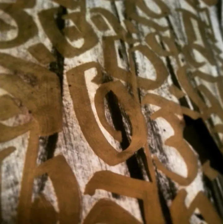 Close-up of large gold blackletter strokes on weathered wood