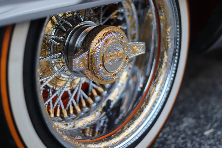 A gold wire wheel and whitewall tyre