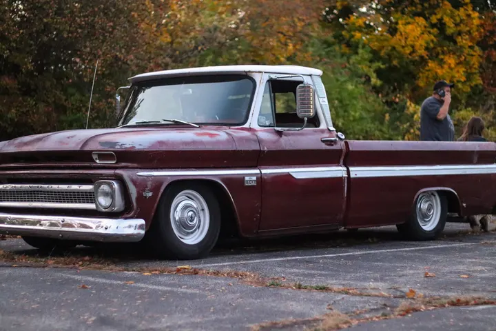 A dark red 1960s Chevrolet C10 pickup in autumn