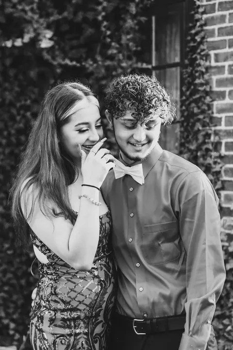 A couple in formal wear laughing, in black and white