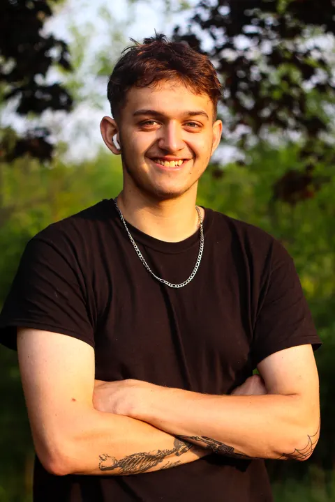 A young man smiling with his arms crossed