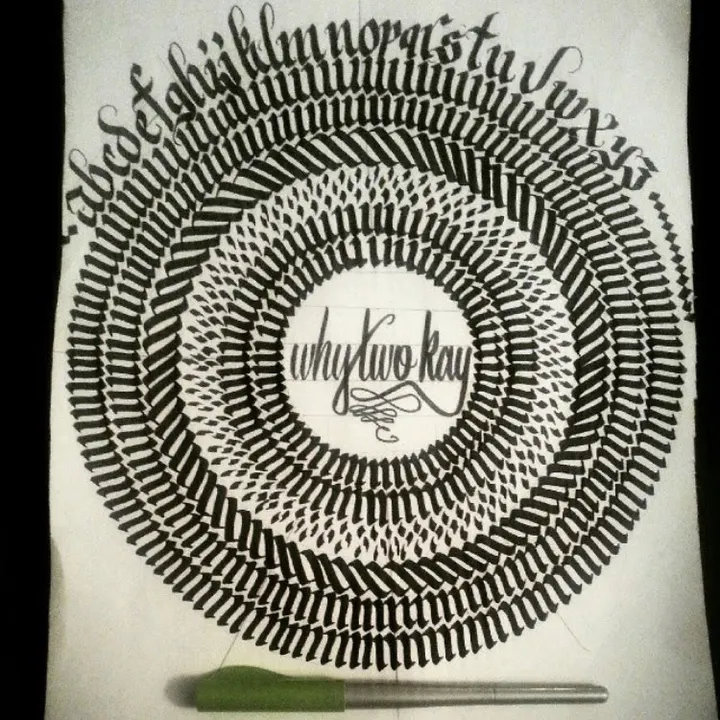 Rings of black blackletter strokes around a small lettered centre, with the alphabet across the top